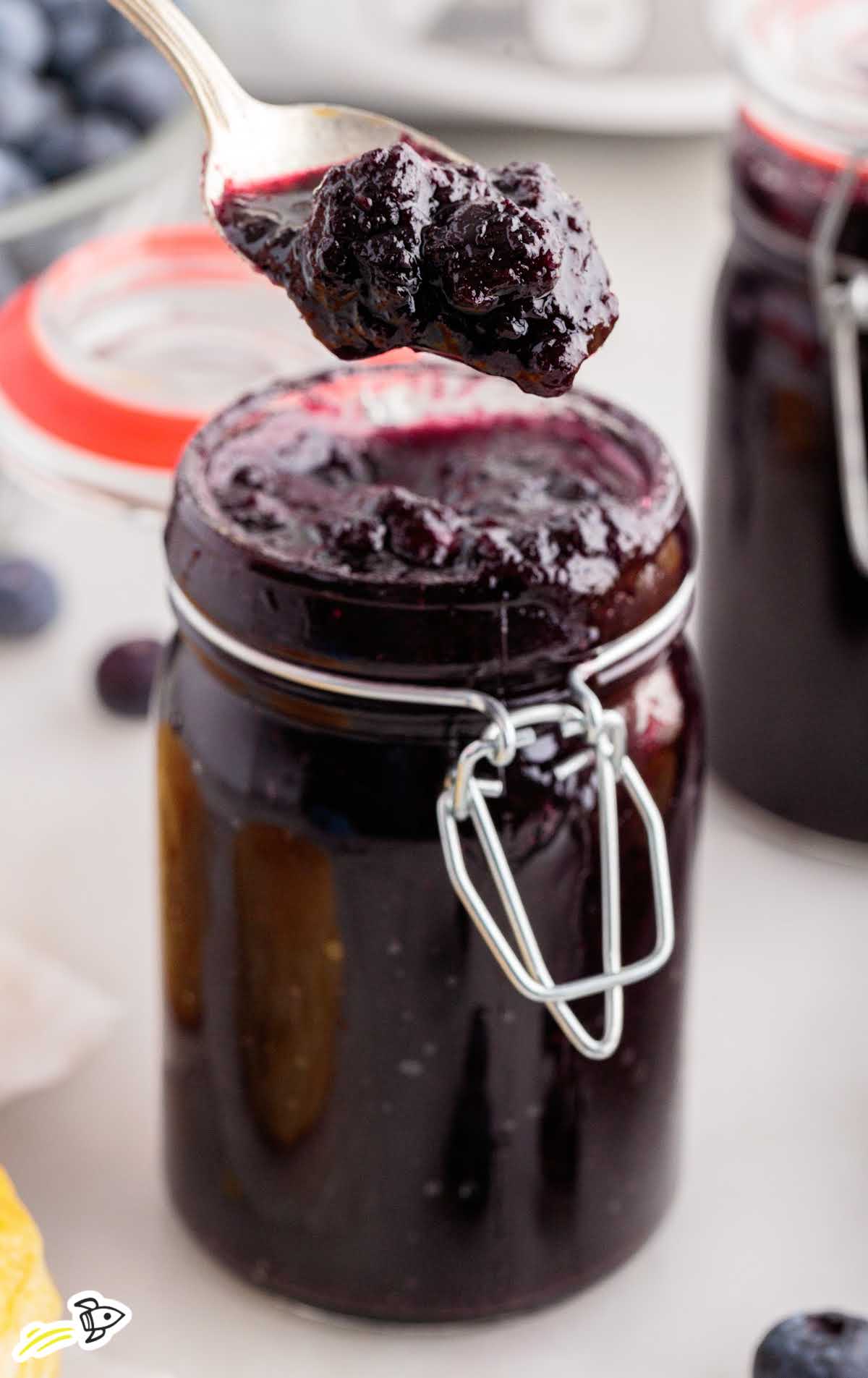 a close up shot of Blueberry Butter in a jar with a spoon grabbing a piece