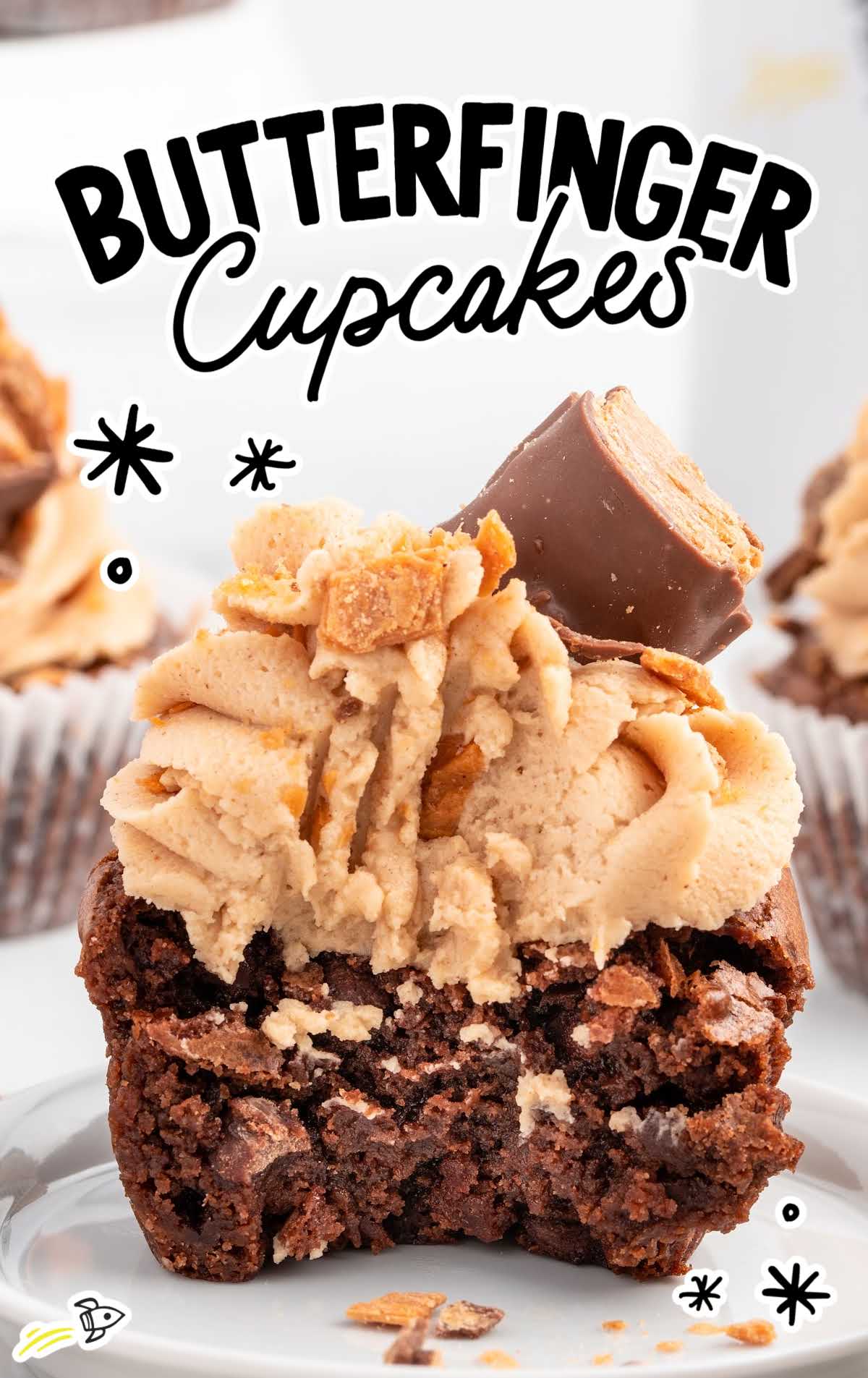 a close up shot of a Butterfinger Cupcake with a bite taken out of it on a plate
