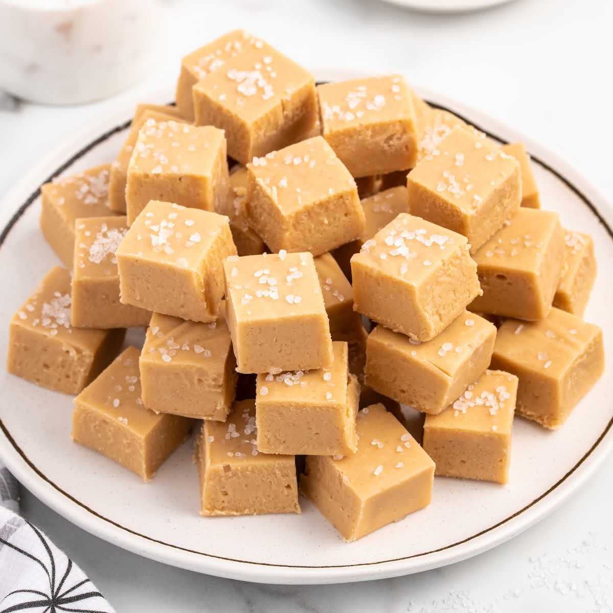 a close up shot of a bunch of Caramel Fudge stacked on top of each other on a plate