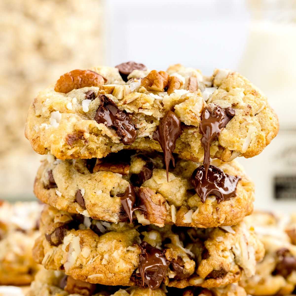 a close up shot of Cowboy Cookies stacked on top of each other with one having a bite taken out of it