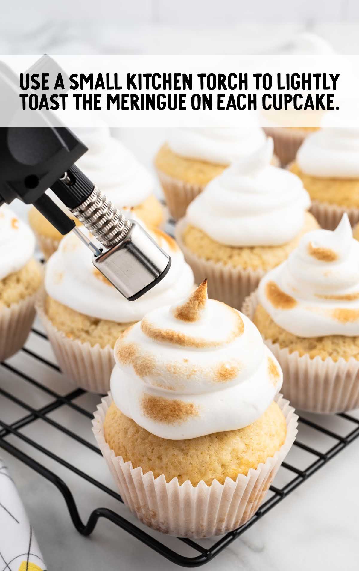 using a kitchen torch toast the meringue on the cupcakes