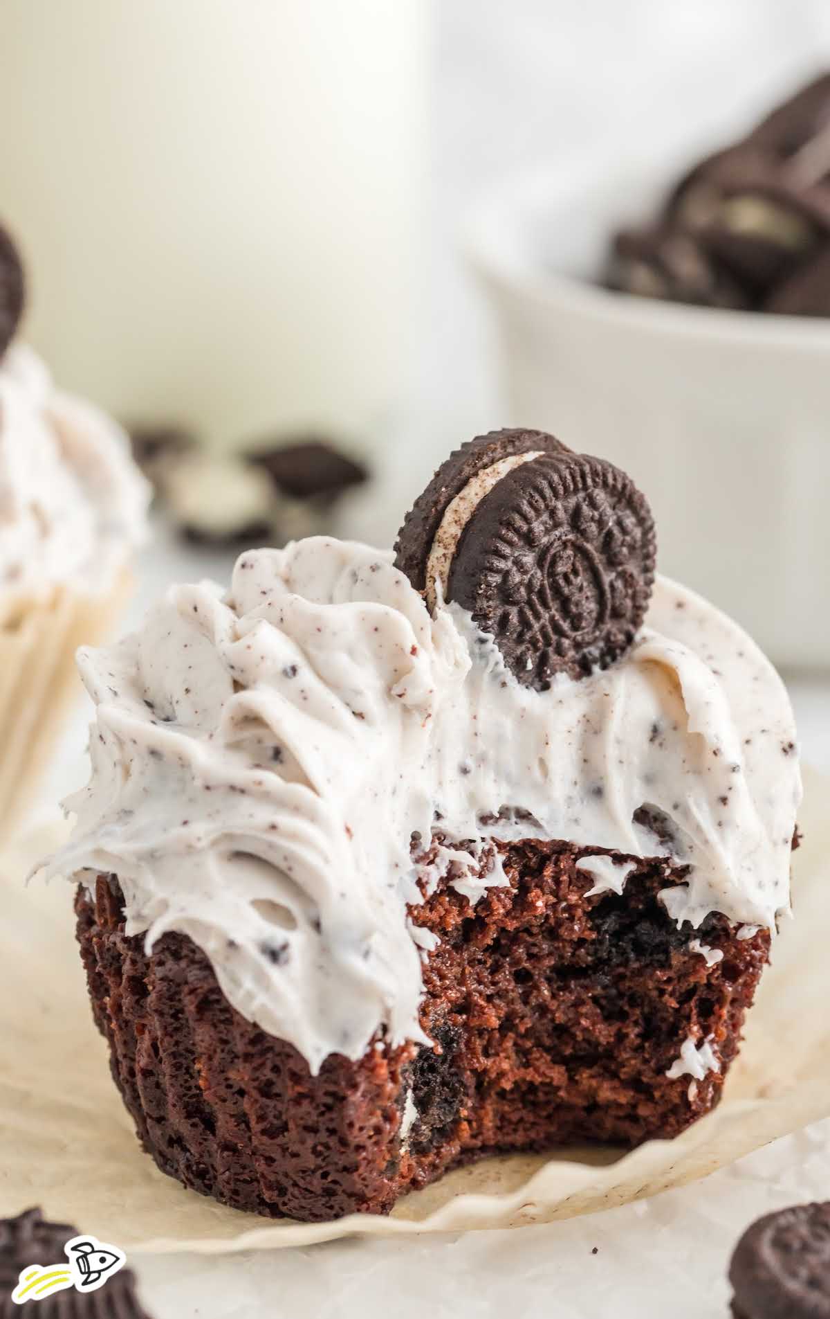 a close up shot of a Oreo Cupcake with a bite taken out of it