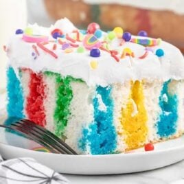 a close up shot of a slice of Rainbow Jello Cake on a plate