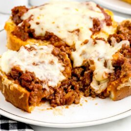 a close up shot of Texas Toast Sloppy Joes on a plate with one having a bite taken out of it