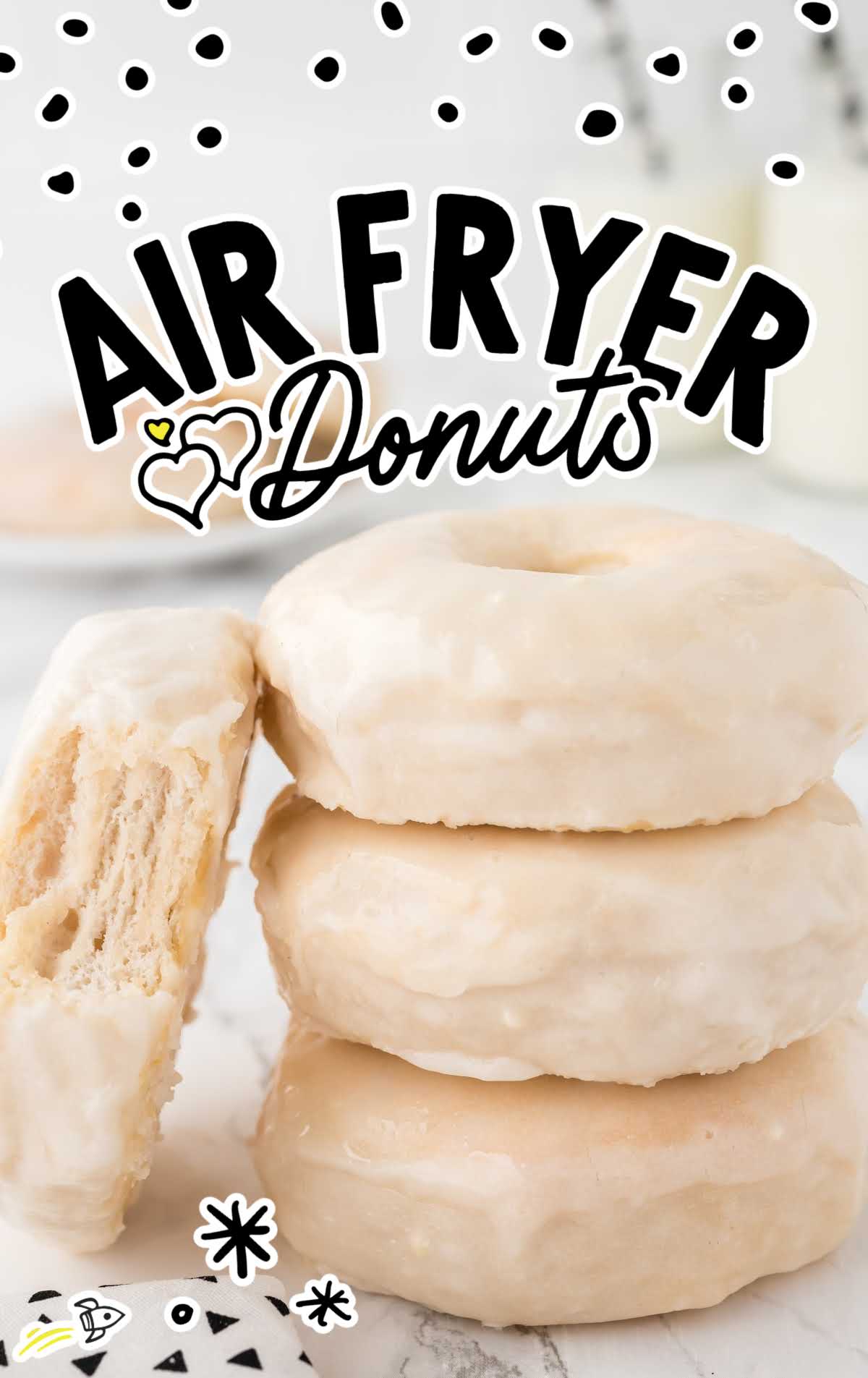 a close up shot of Air Fryer Donuts stacked on top of each other with one on the side with a bite taken out of it