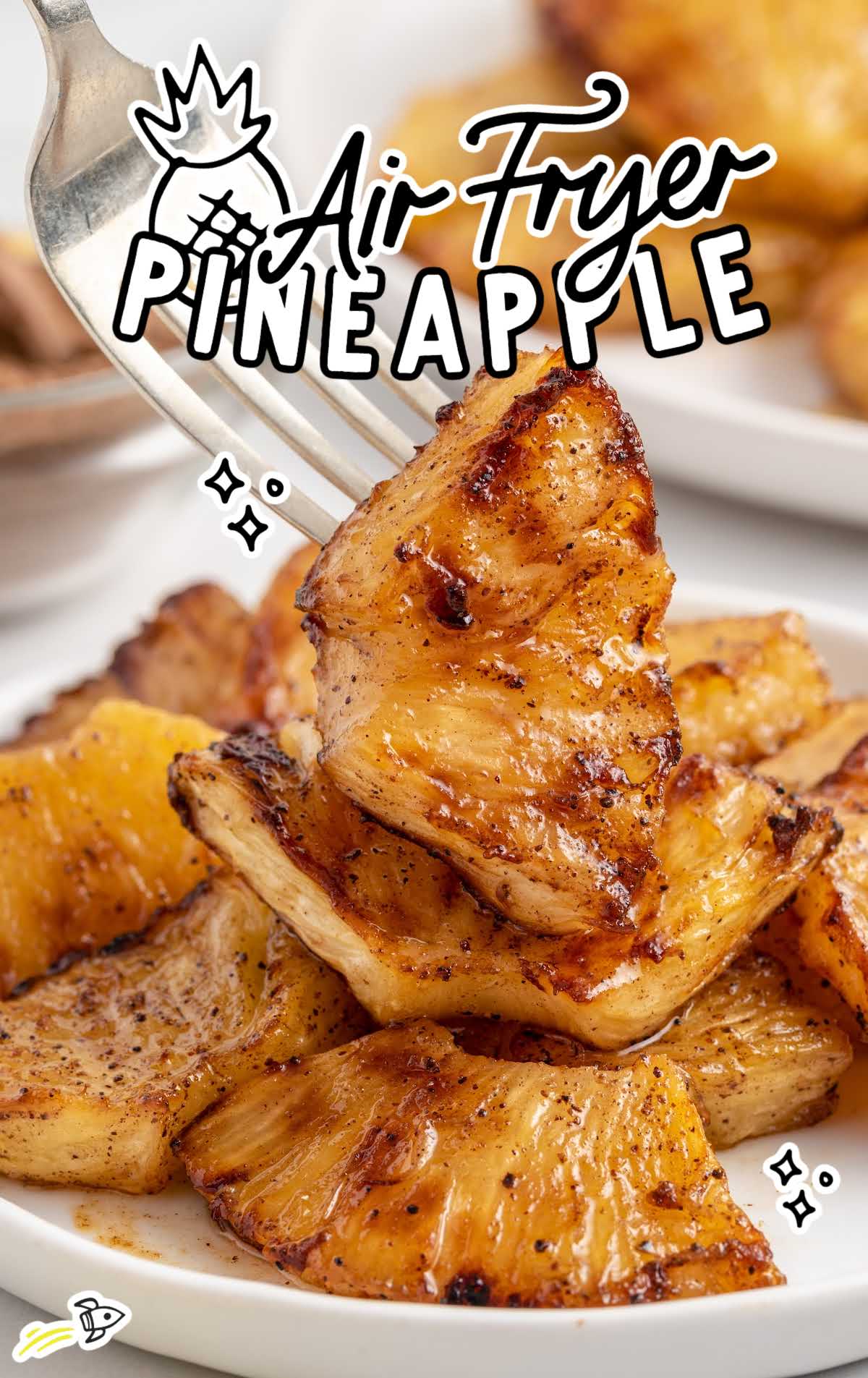 close up shot of Air Fryer Pineapples on a plate with one being picked up by a fork