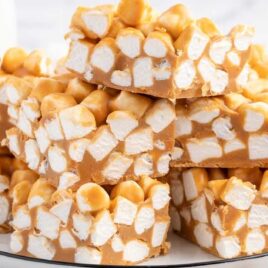 a close up shot of Butterscotch Marshmallow Bars stacked on top of each other on a plate