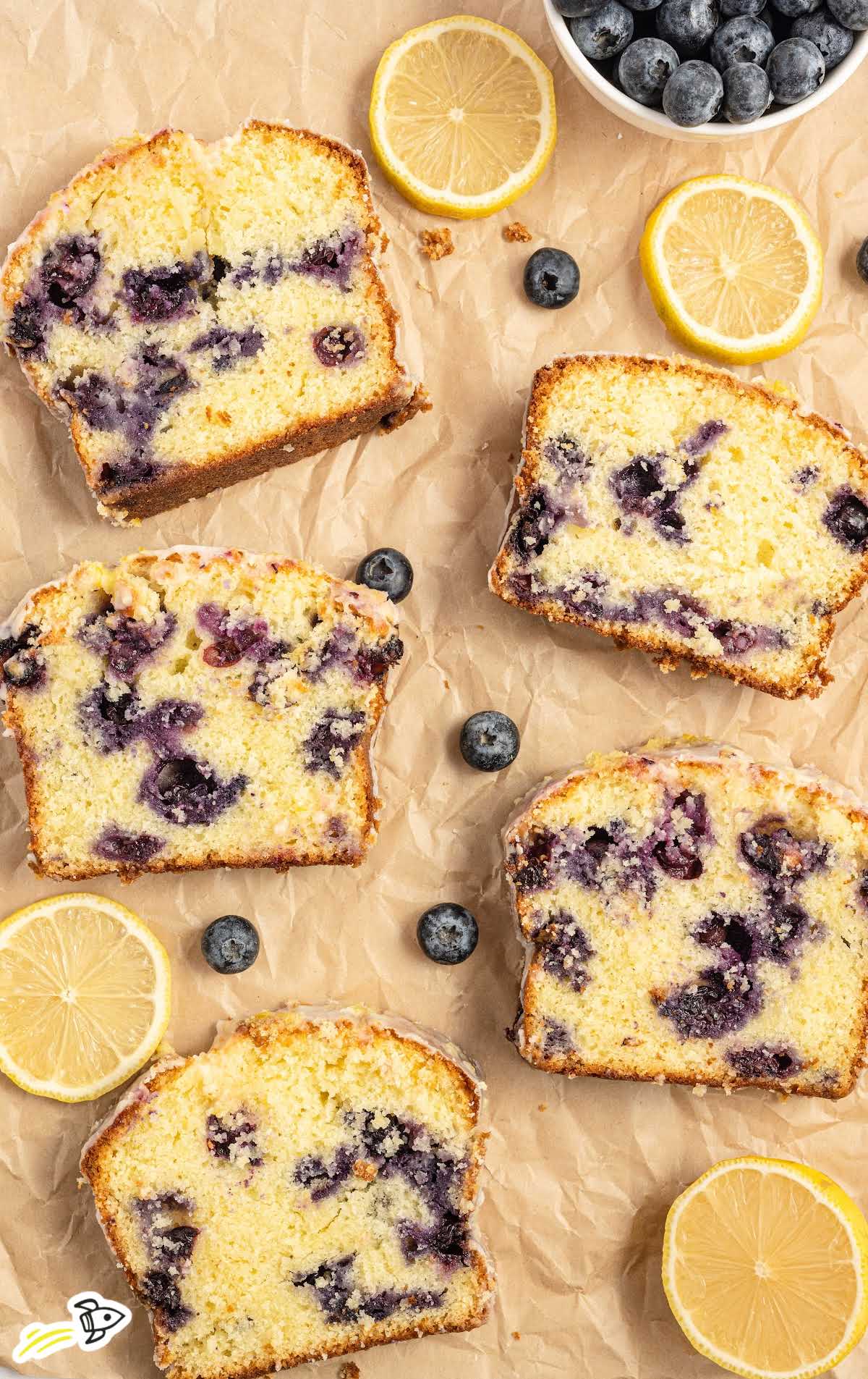 close up shot slices of pound cake topped with glaze and blueberries on a wooden board