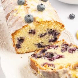 close up shot of a loaf of pound cake topped with glaze and blueberries