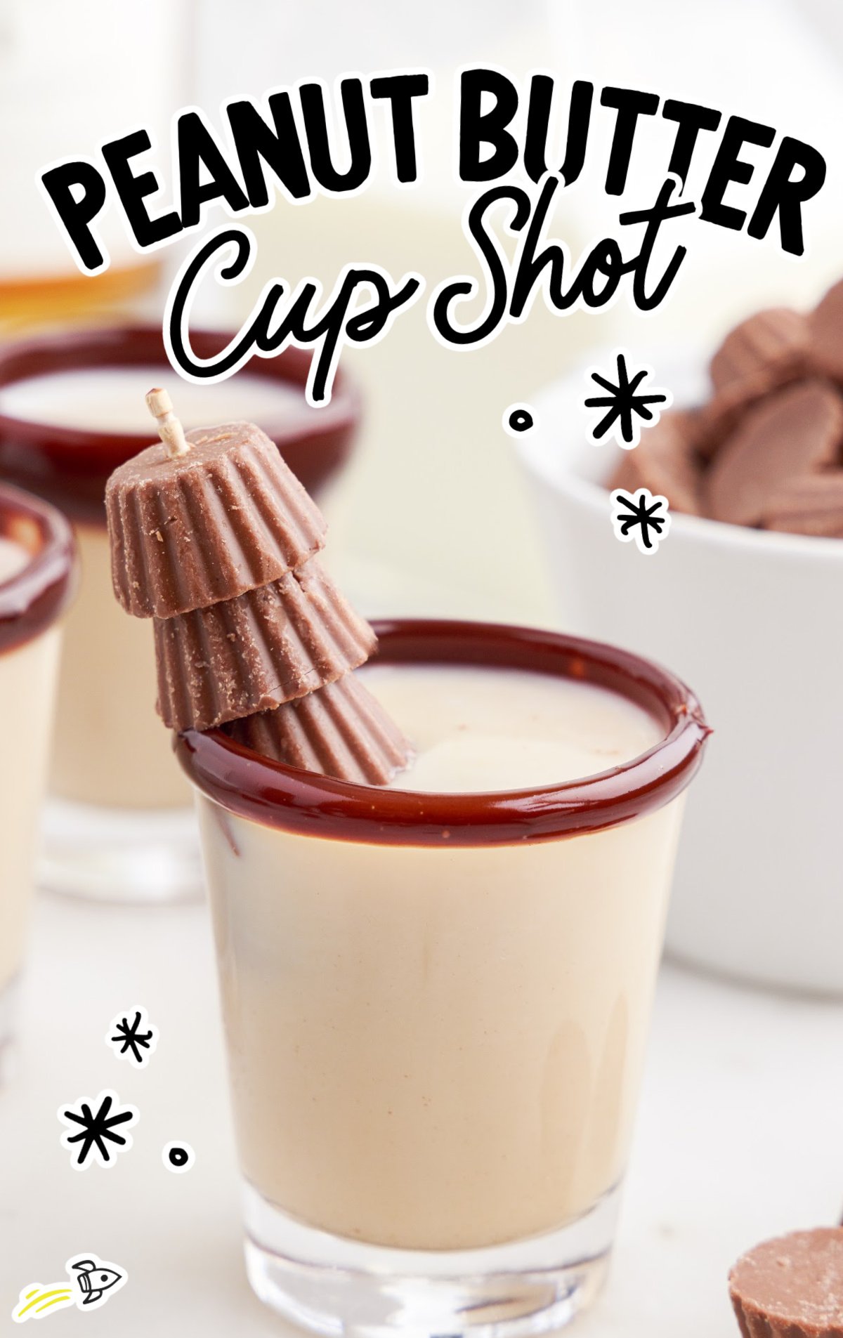 A peanut butter cup shot in a glassed rimmed with chocolate and with mini peanut butter cups as a garnish.