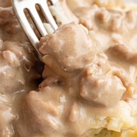 Fork digging into hearty hamburger gravy over mashed potatoes, text overlay reads “The Best Ever Hamburger Gravy – Family Friendly Recipe.”