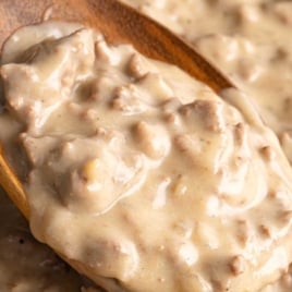 Spoonful of thick hamburger gravy held over a skillet, text overlay reads “How to Make Thick & Creamy Hamburger Gravy – Best Recipe!”