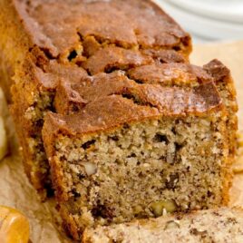close up shot of a loaf of banana bread with a slice of banana bread