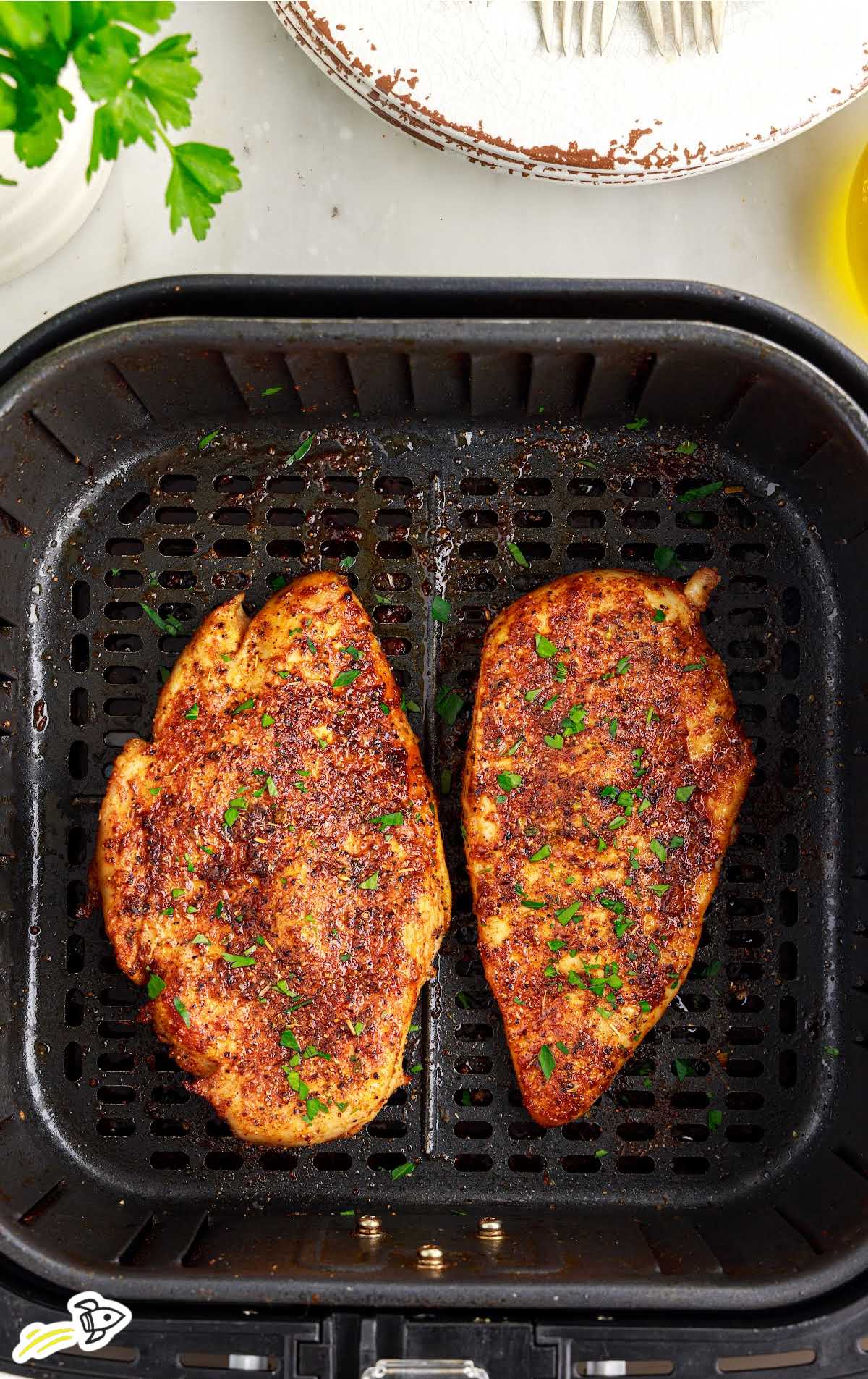 overhead shot of a couple of pieces of Air Fryer Chicken Breasts in a air fryer