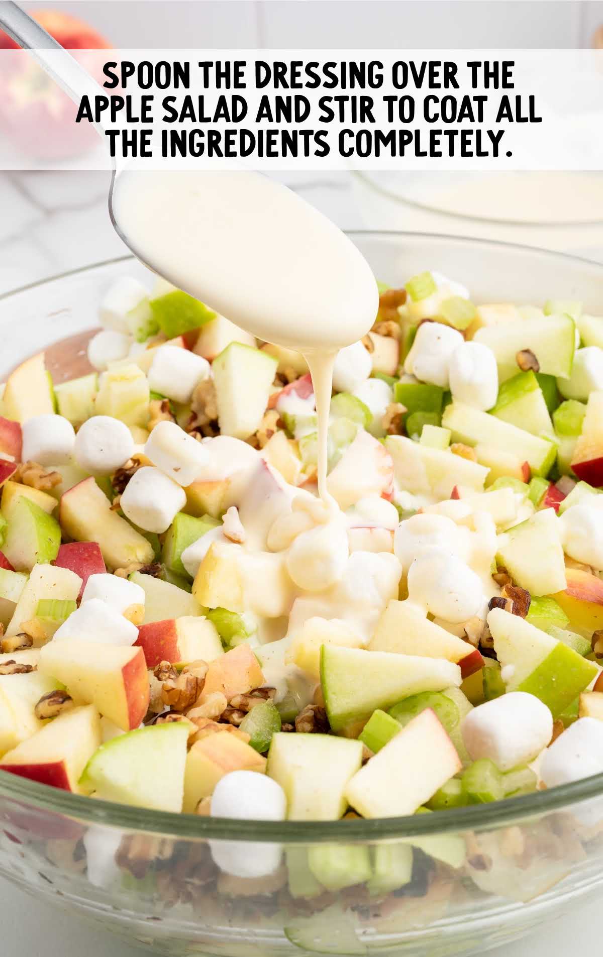 dressing spoon over the apple salad in a bowl