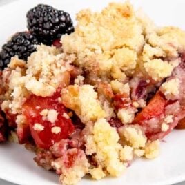 a slice of crumble on a plate with blackberries