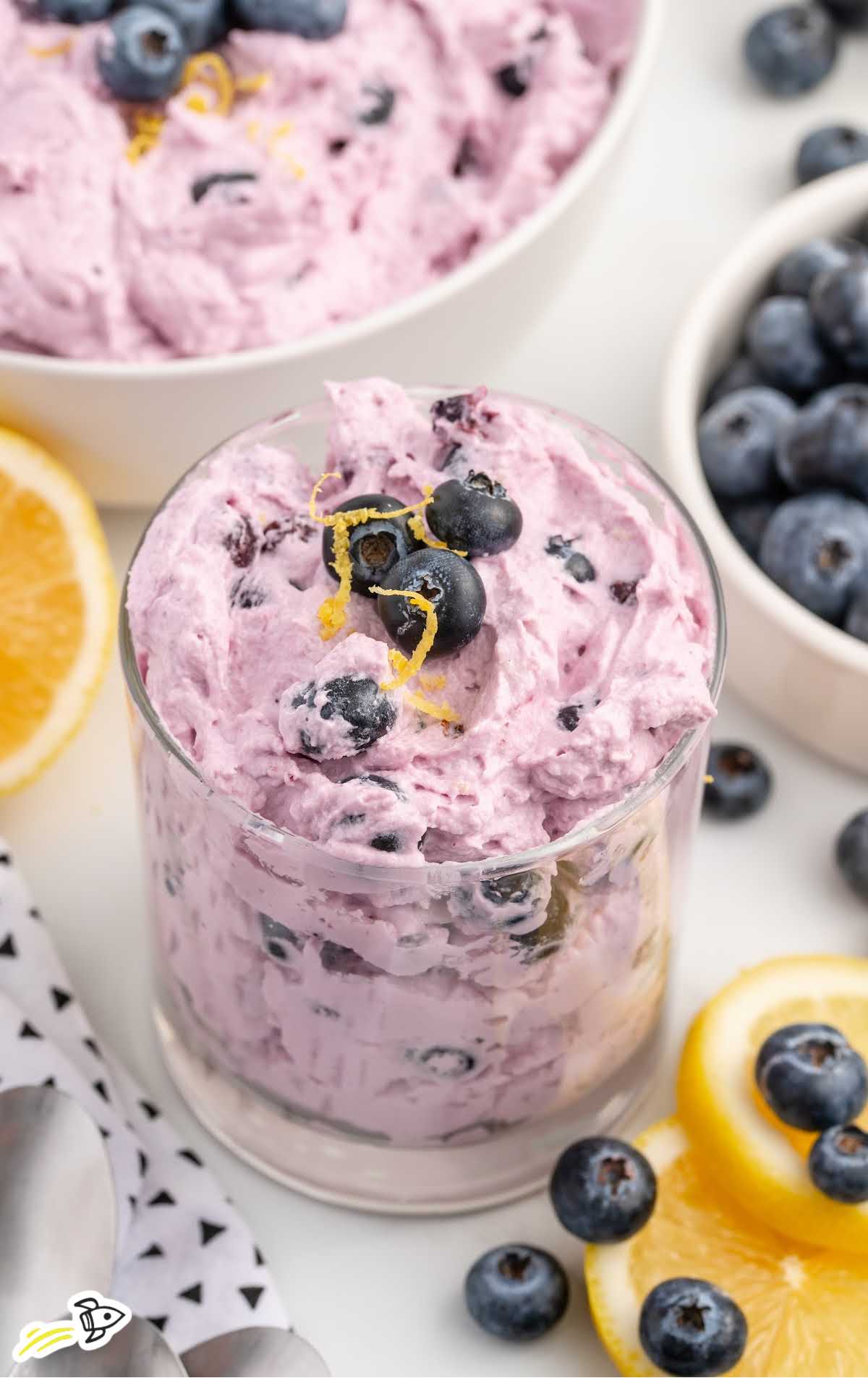 a close up shot of Blueberry Fluff in a cup topped with blueberries and lemon zest