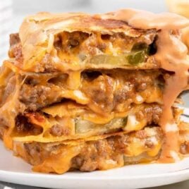 close up shot of Cheeseburger Quesadilla stacked on top of each other and drizzled with burger sauce on a plate