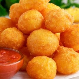close up shot of Fried Cheese Balls piled on a plate with dipping sauce
