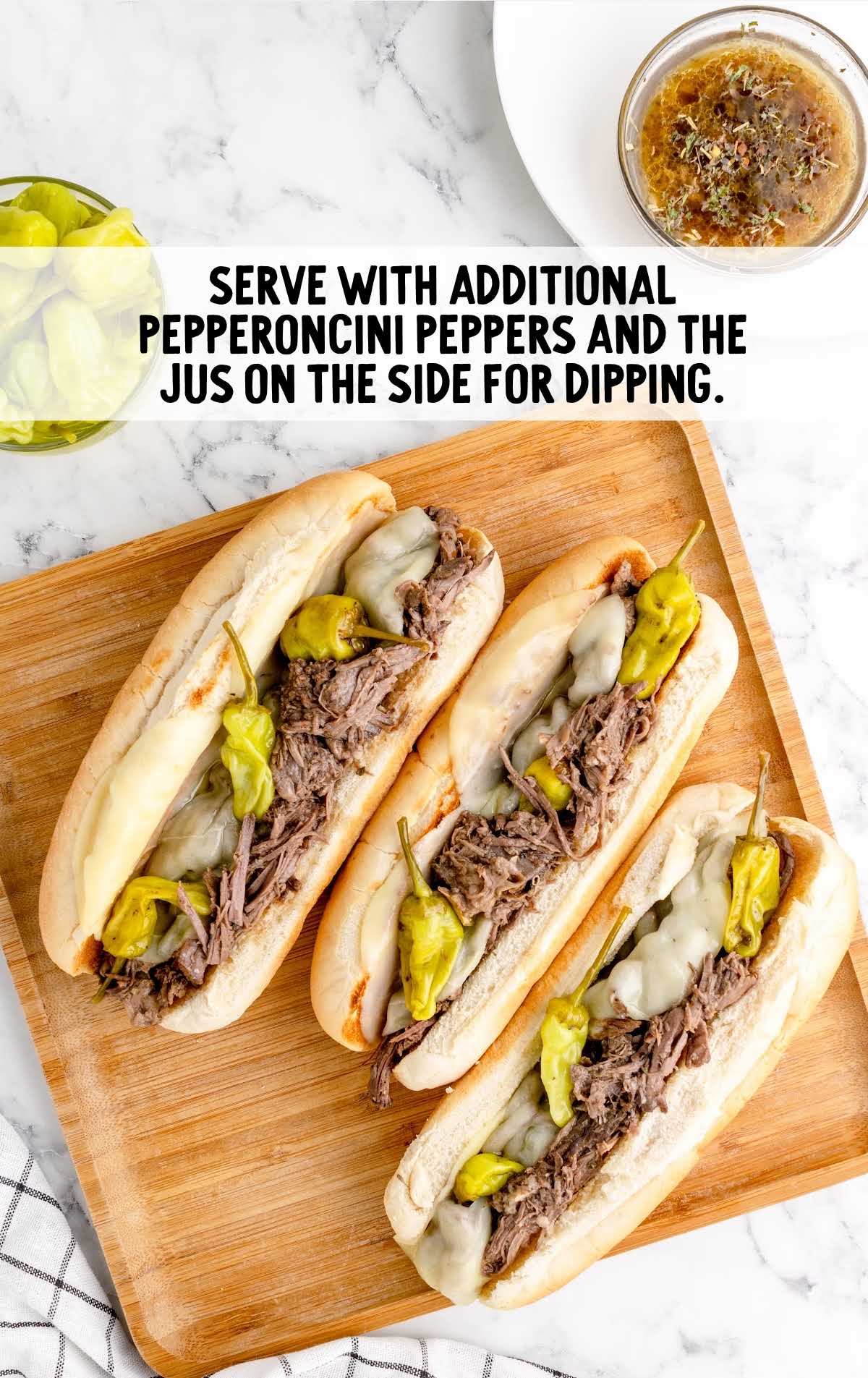 beef placed in a sub with pepperoncini peppers and beefy jus on the side