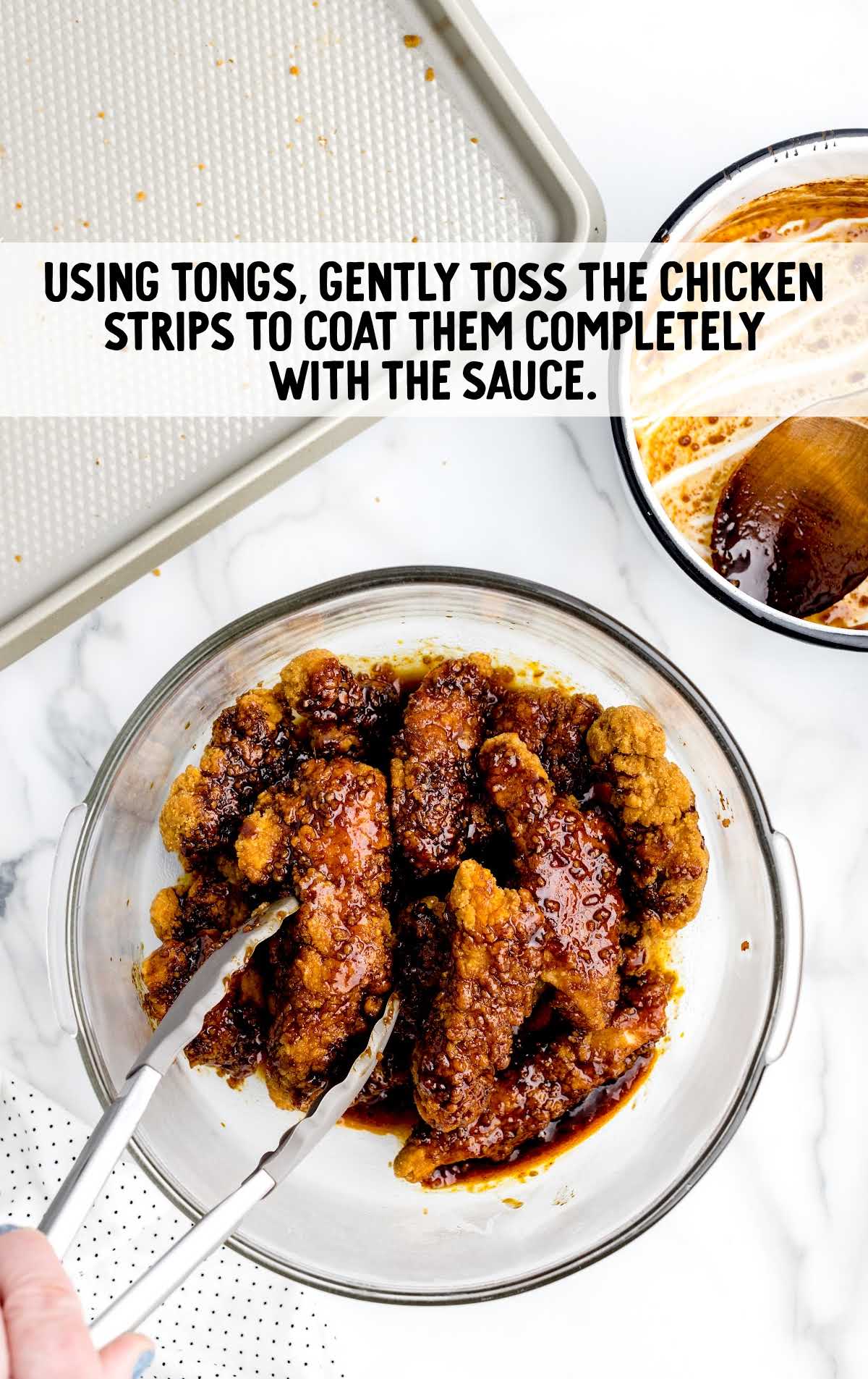 toss chicken strips into the sauce using tongs