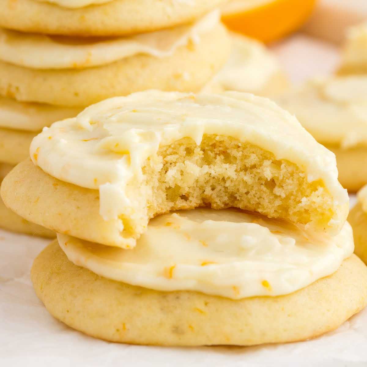 a close up shot of Orange Cookies stacked on top of each other with one having a bite taken out