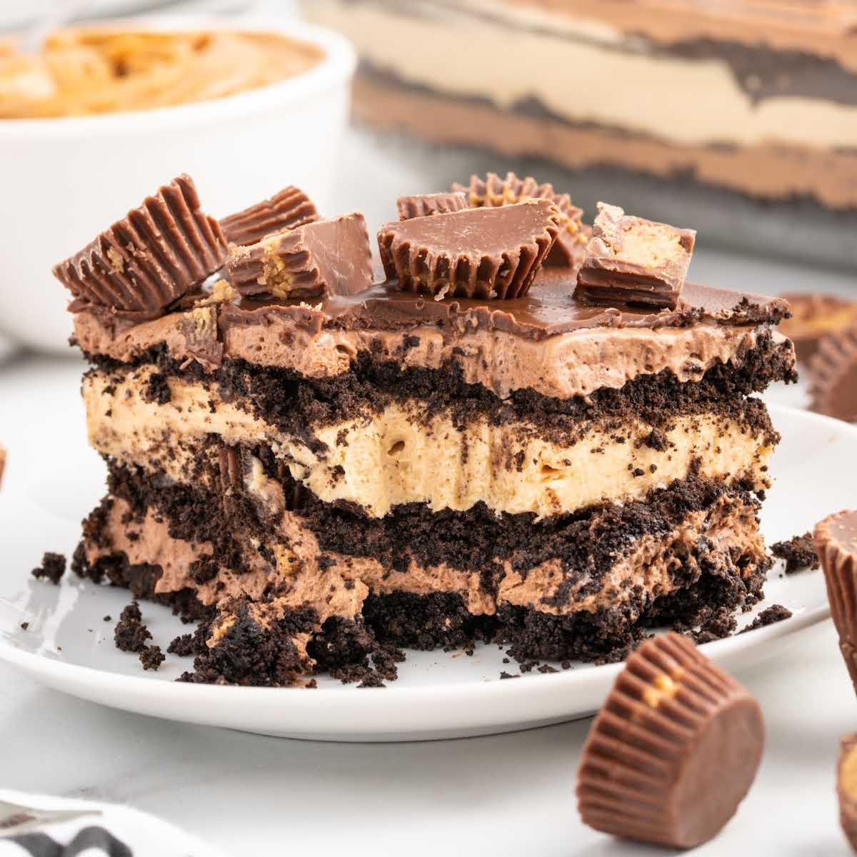 close up shot of a slice of Peanut Butter Cake topped with peanut butter Reeses on a plate