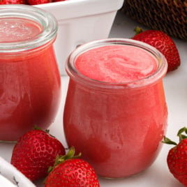 Strawberry curd filling a glass jar to the top.