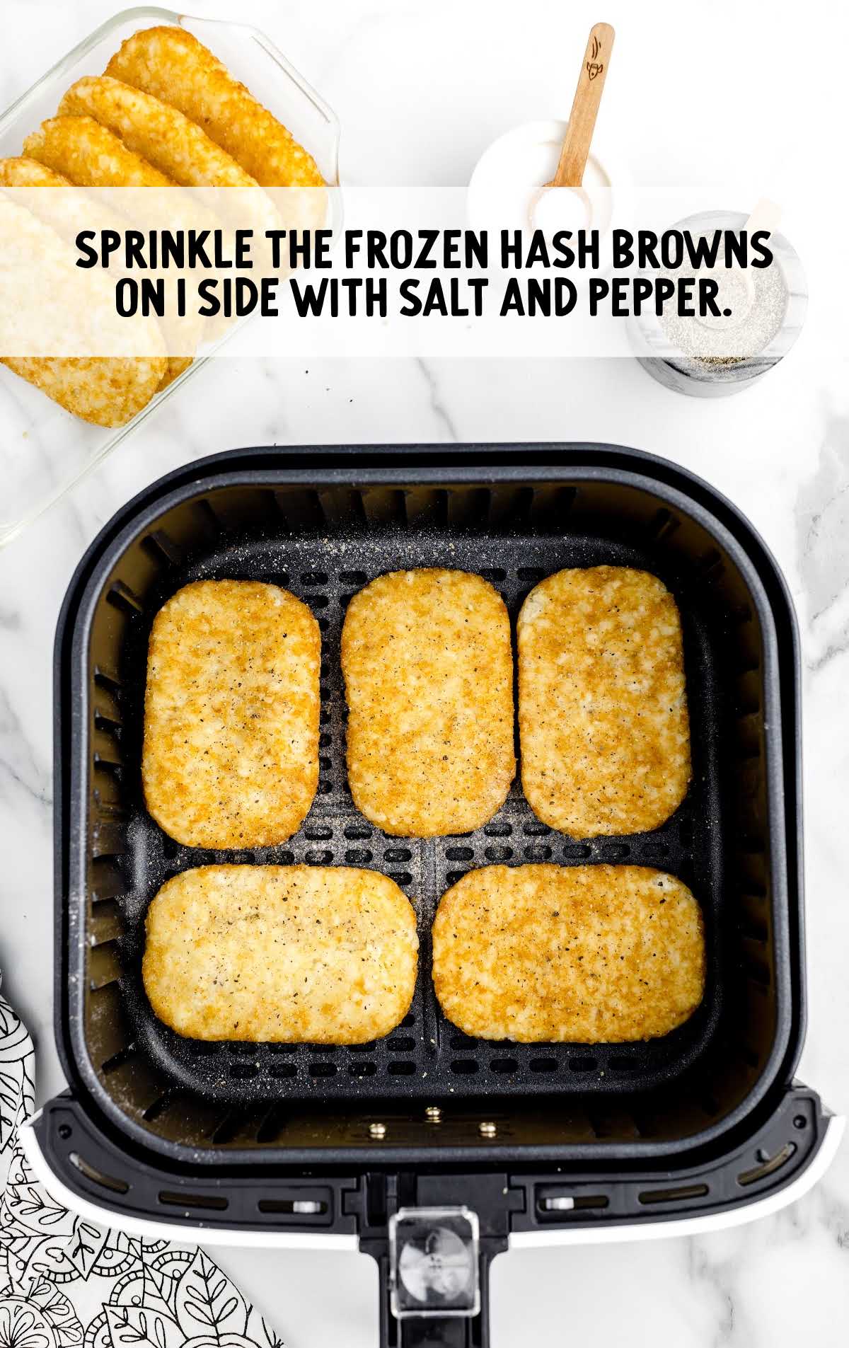 hash browns placed into an air fryer and sprinkled with salt and pepper 