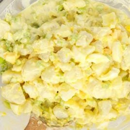 overhead shot of Amish Potato Salad in a bowl with a wooden spoon