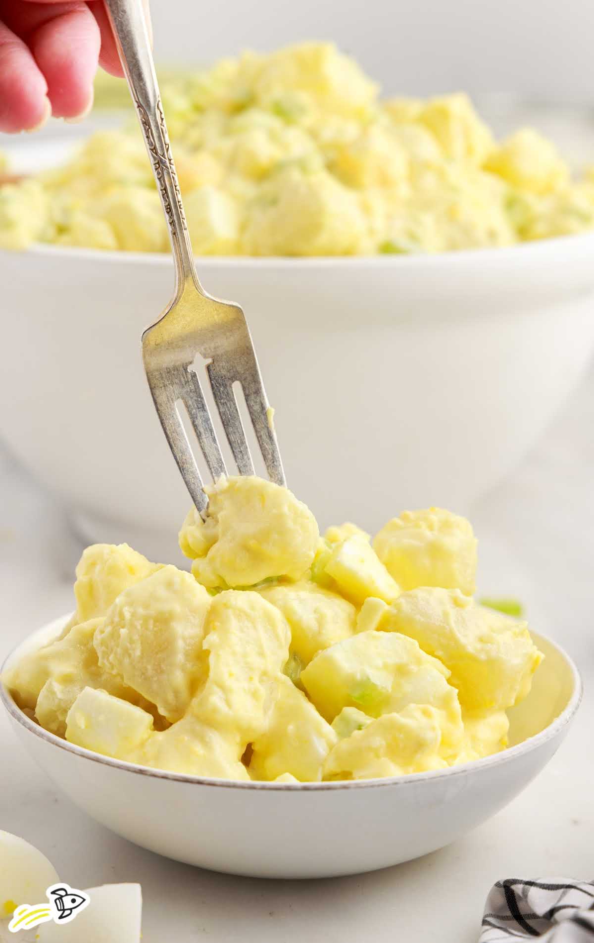 a close-up shot of Amish Potato Salad in a bowl with a fork grabbing. a piece