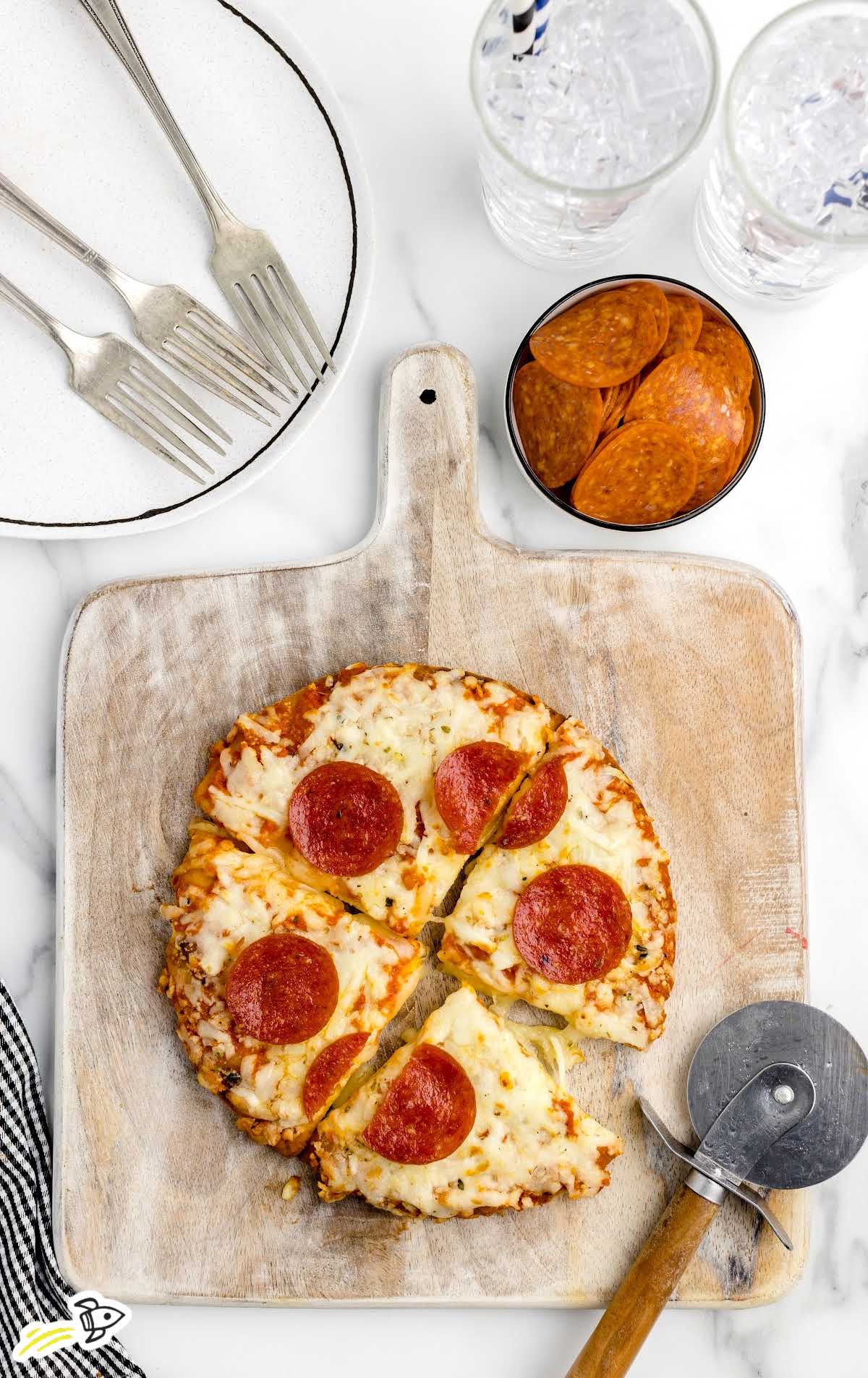 overhead shot of a cooked pizza cut with a pizza cutter on a wooden board