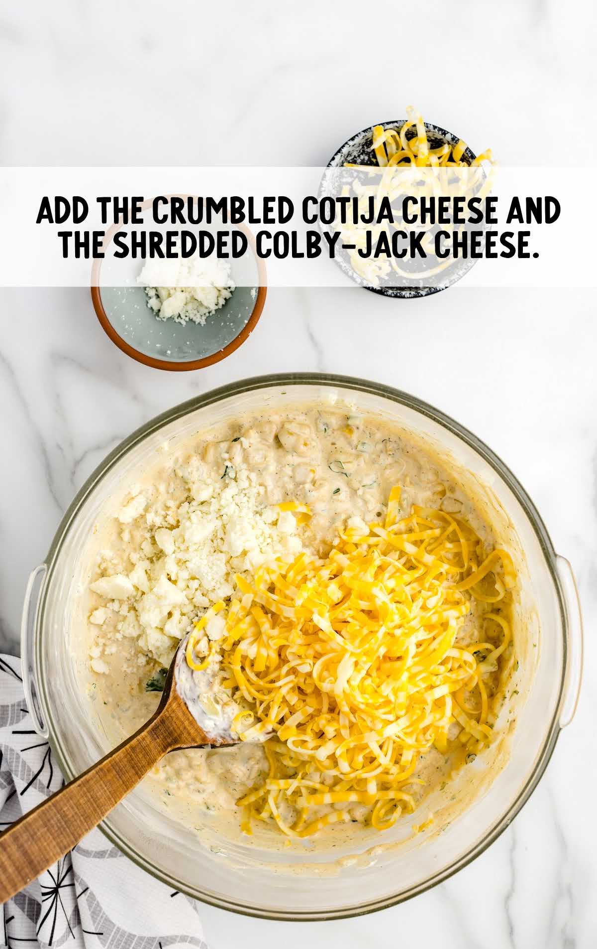 crumbled cotija cheese and shredded Colby jack cheese added to the ingredients in the bowl