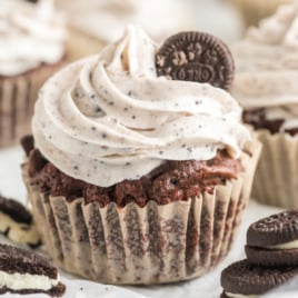 An oreo cupcake garnished with frosting and a mini oreo.