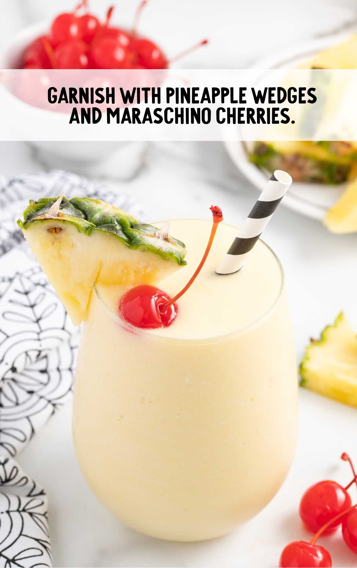 a glass of Pina colada garnished with pineapple wedges and the maraschino cherries