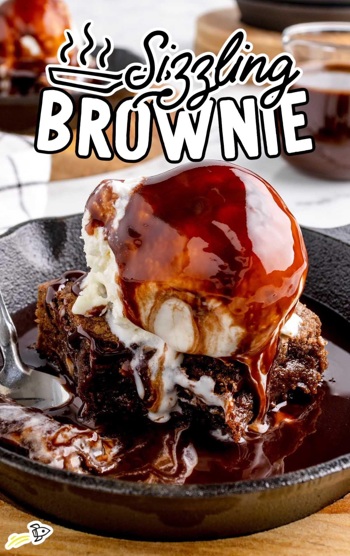 a close-up shot of a sliced of Sizzling Brownie in a pan with a spoon