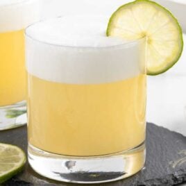 a glass of Tequila Sour garnished with a slice of lime