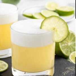 a glass of Tequila Sour garnished with a slice of lime