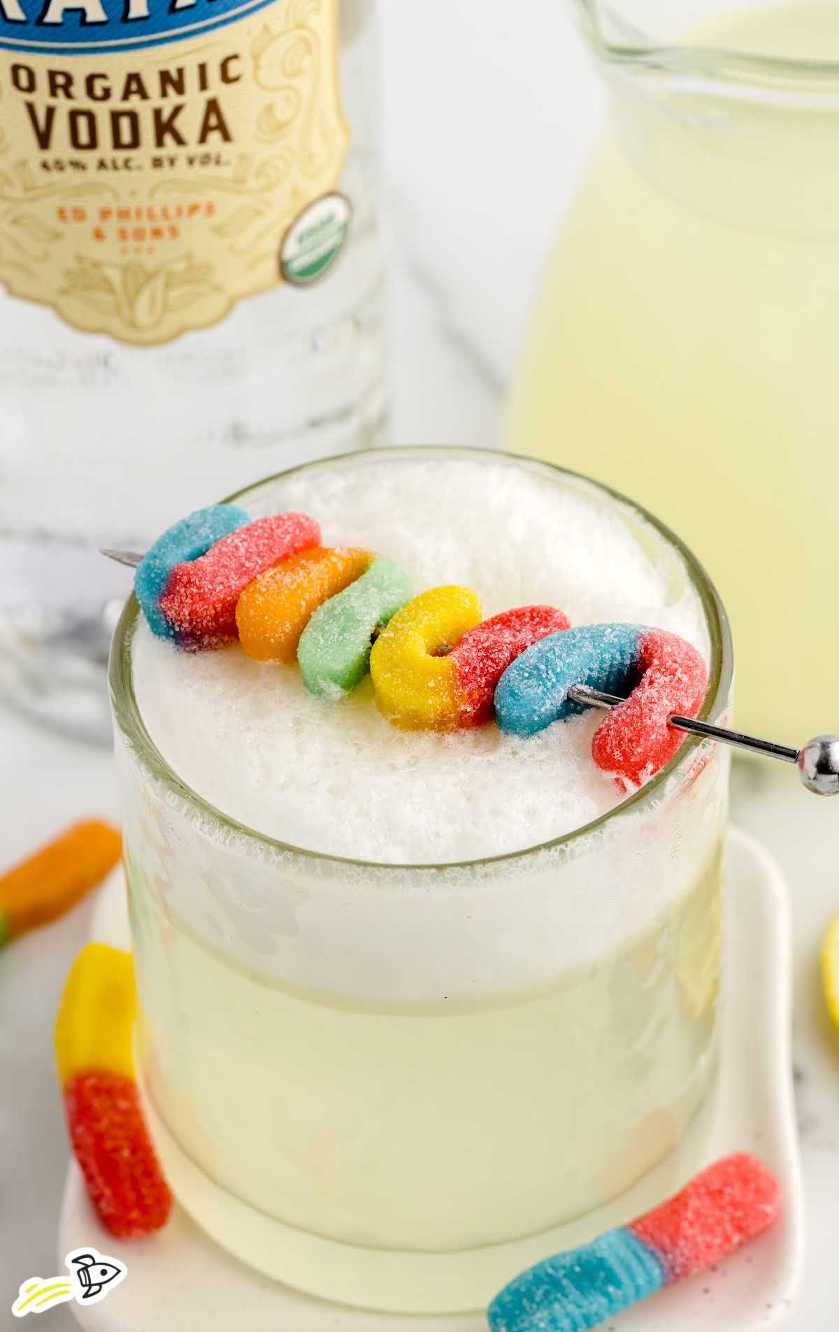close up shot of a glass of vodka sour garnished with candies
