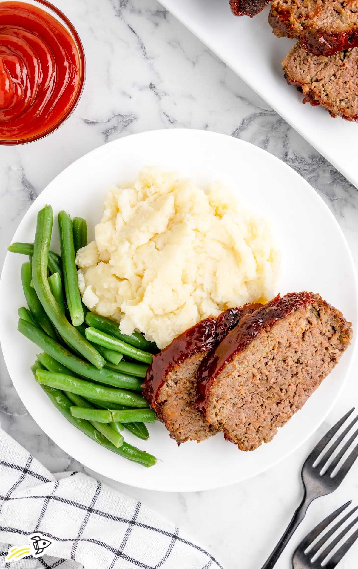 a close up shot of slices of Air Fryer Meatloaf on a plate with mashed potatoes and green beens
