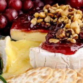 close shot of Baked Brie topped with Jam and walnuts served with crackers
