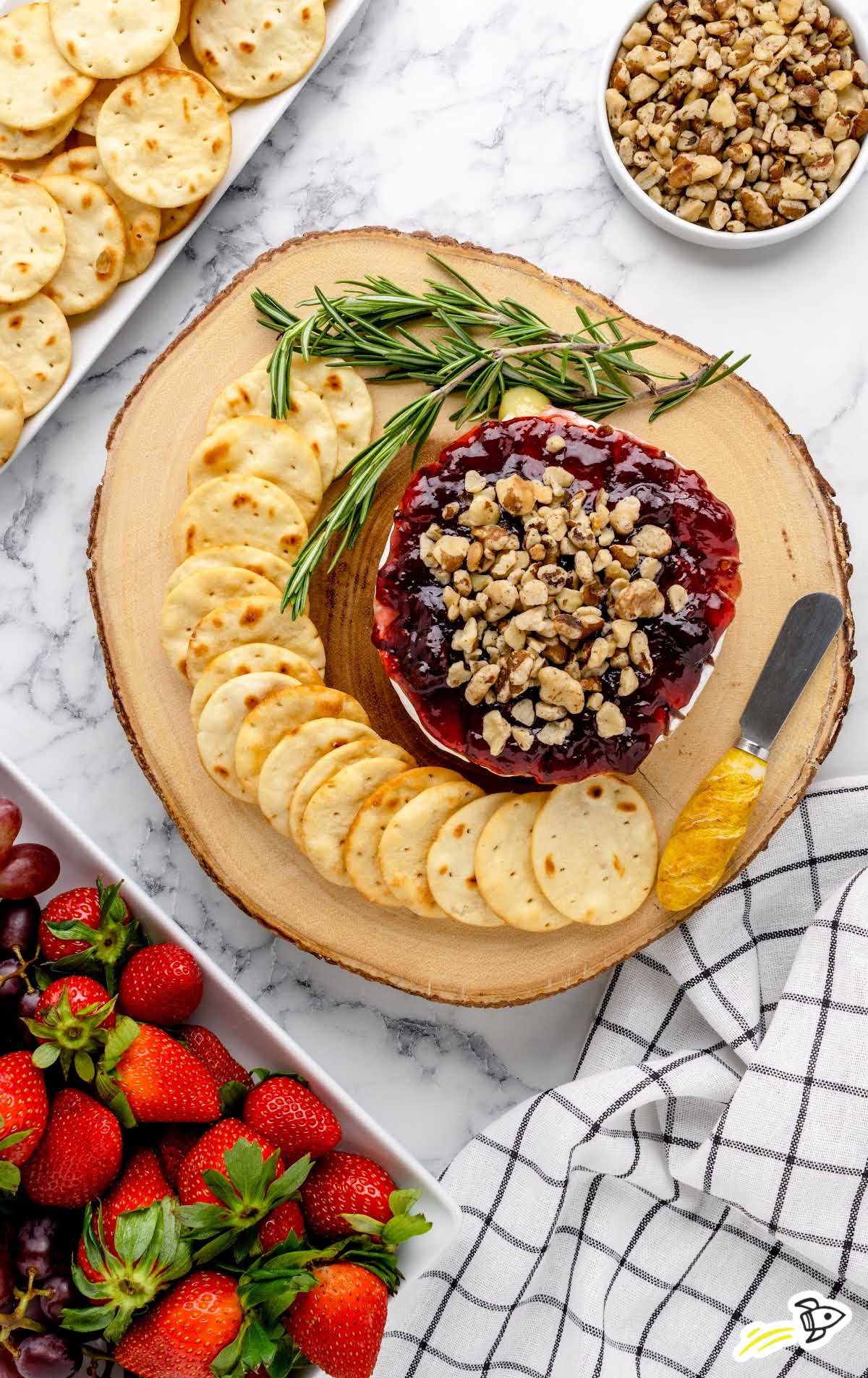 overhead shot of Baked Brie topped with Jam and walnuts served with crackers
