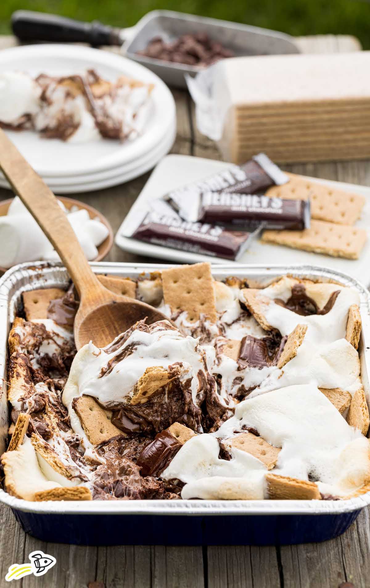 close up shot of a pan of smores nachos with a large wooden spoon