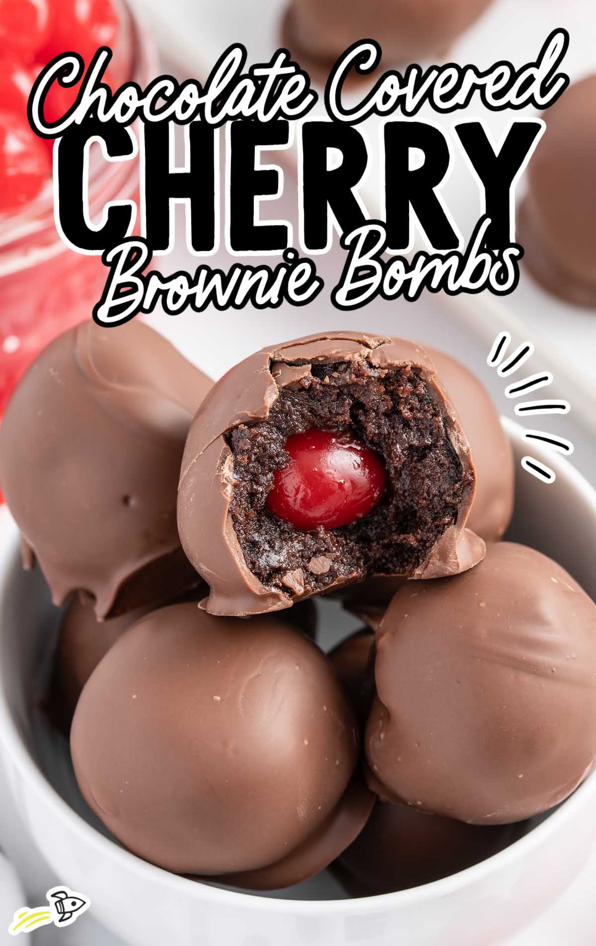 close up shot of a bowl of Chocolate Covered Cherry Brownie Bombs with a bite taken out of one of the brownie bombs