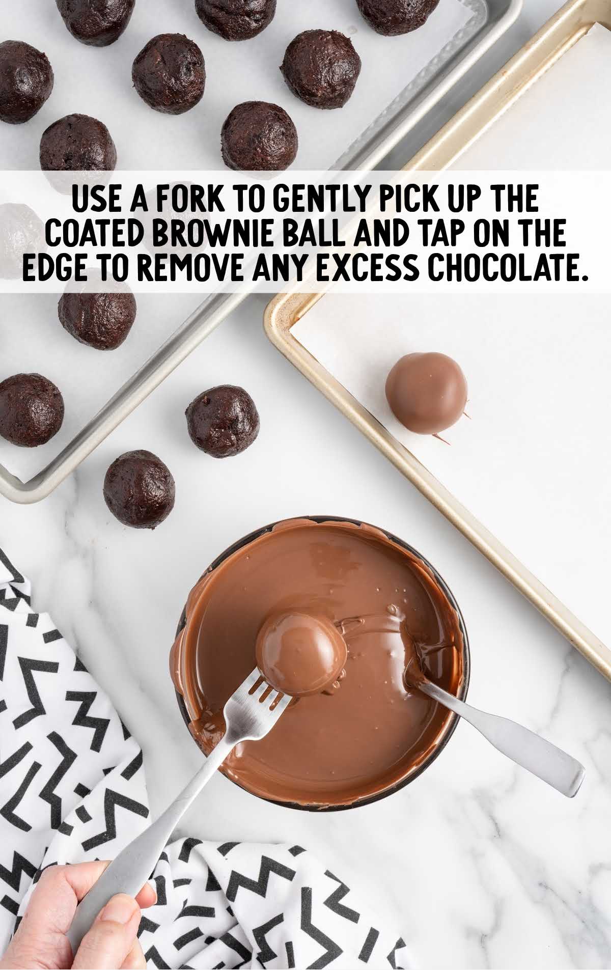 brownie ball dipped into a bowl of melted chocolate than picked up with a fork