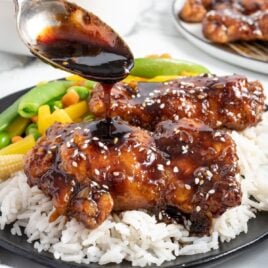 close up shot of a plate of honey glazed chicken served with white rice and vegetables