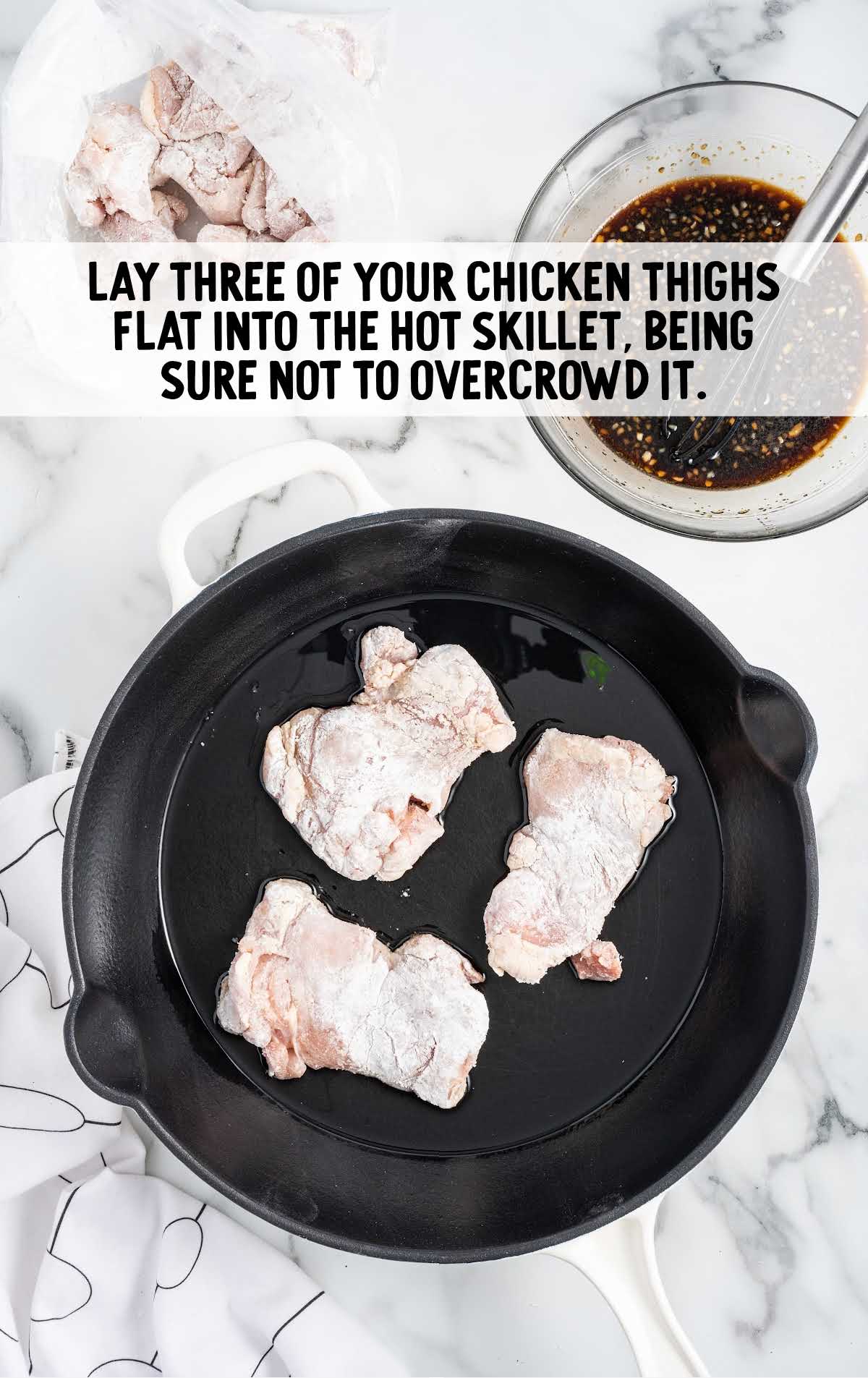chicken thighs place on a skillet of oil