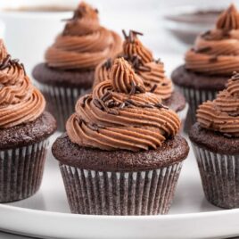 close up shot of a frosted Moist Chocolate Cupcakes topped with chocolate sprinkles on a plate