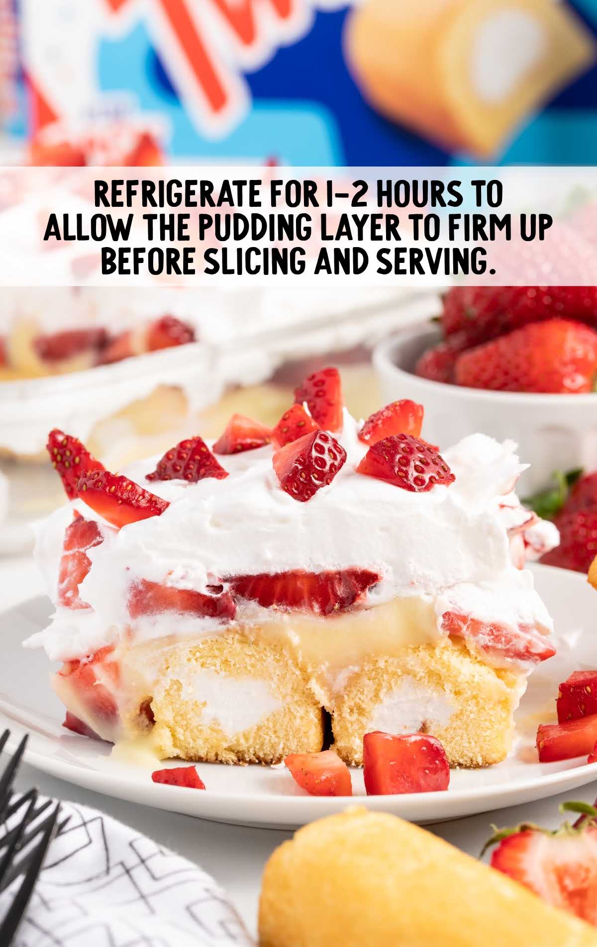 a slice of Twinkie Cake topped with cut up strawberries on a plate