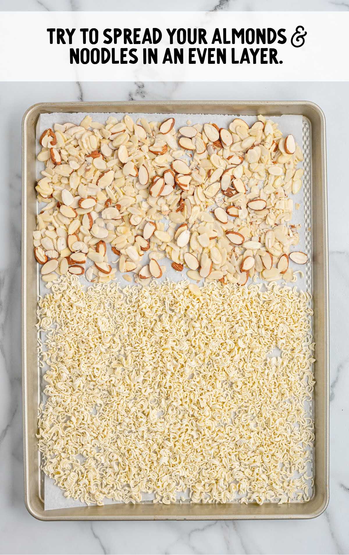 Sheet pan with toasted ramen noodles and sliced almonds spread evenly for baking